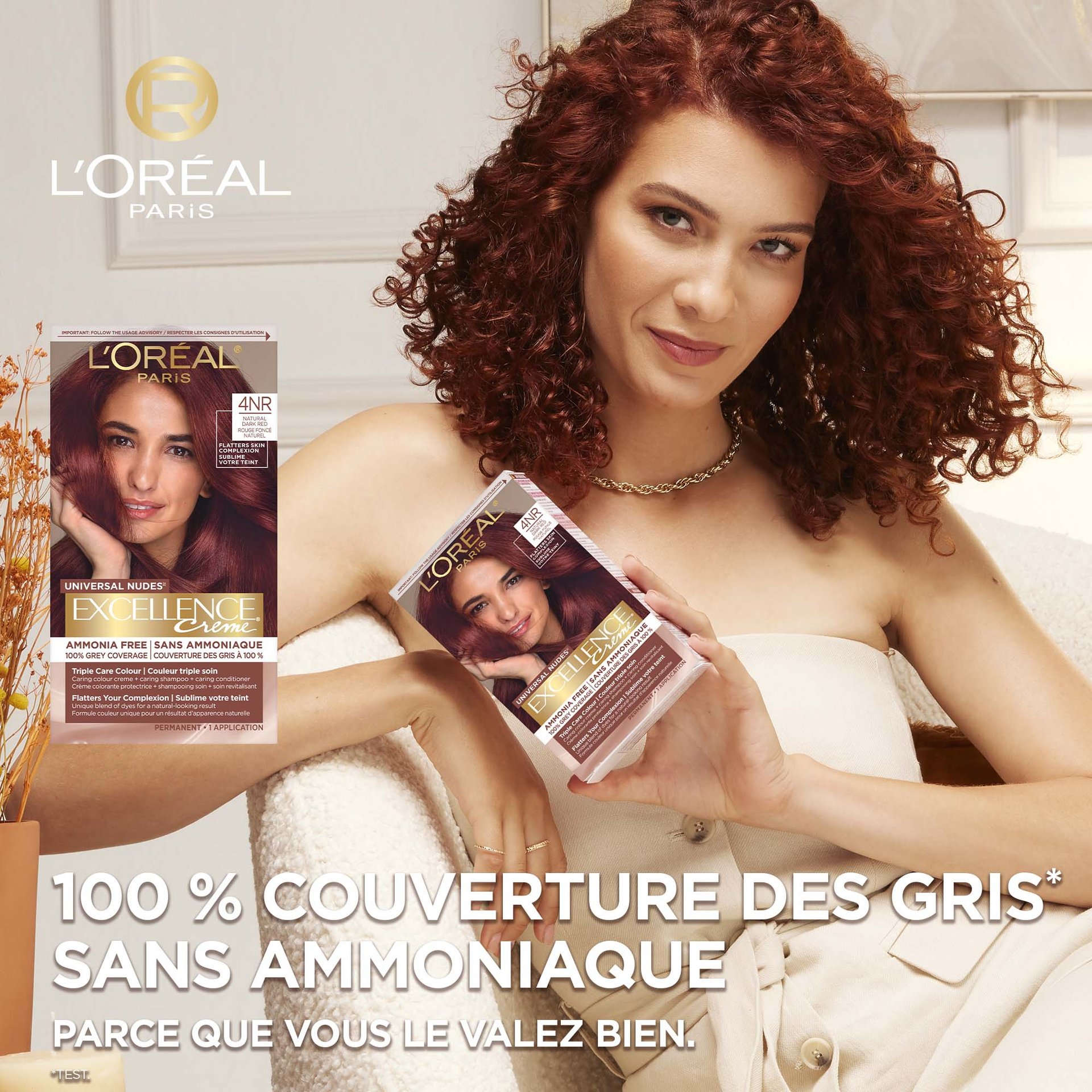 Femme au cheveux rouge qui tient une boîte de coloration Excellence Crème Bronzer qui couvre 100% des cheveux gris